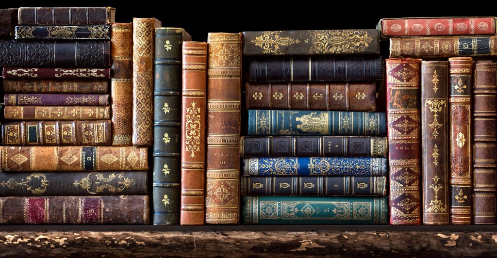 Old books on wooden shelf. Many of beautiful retro book covers, skins. Bookshelf history theme grunge background. Concept on the theme of history, age, retro.